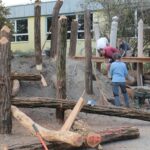 Baumstammmikado wird durch Helfende erbaut