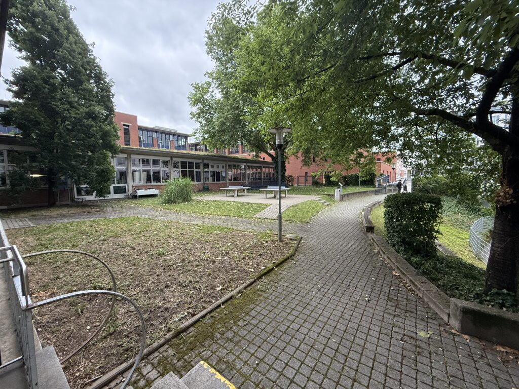 Schulhof mit Bäumen und zwei Tischtennisplatten