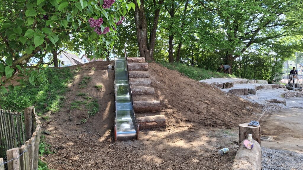 Rutsche mit Baumstammtreppe unter Bäumen