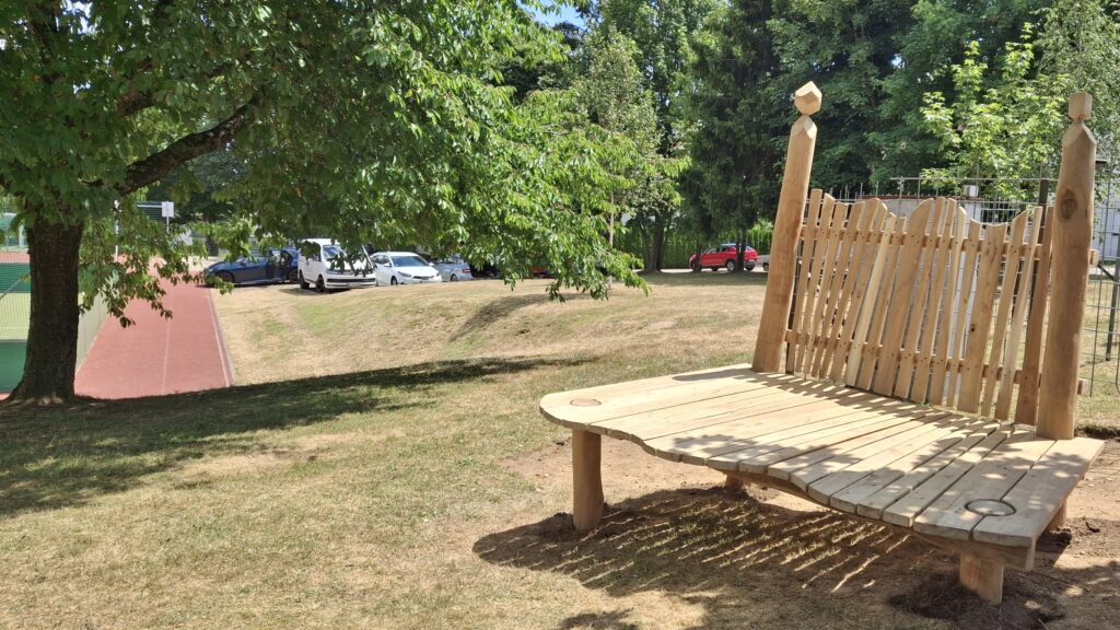 Fertige Holzbank auf einer Wiese vor dem Sportplatz