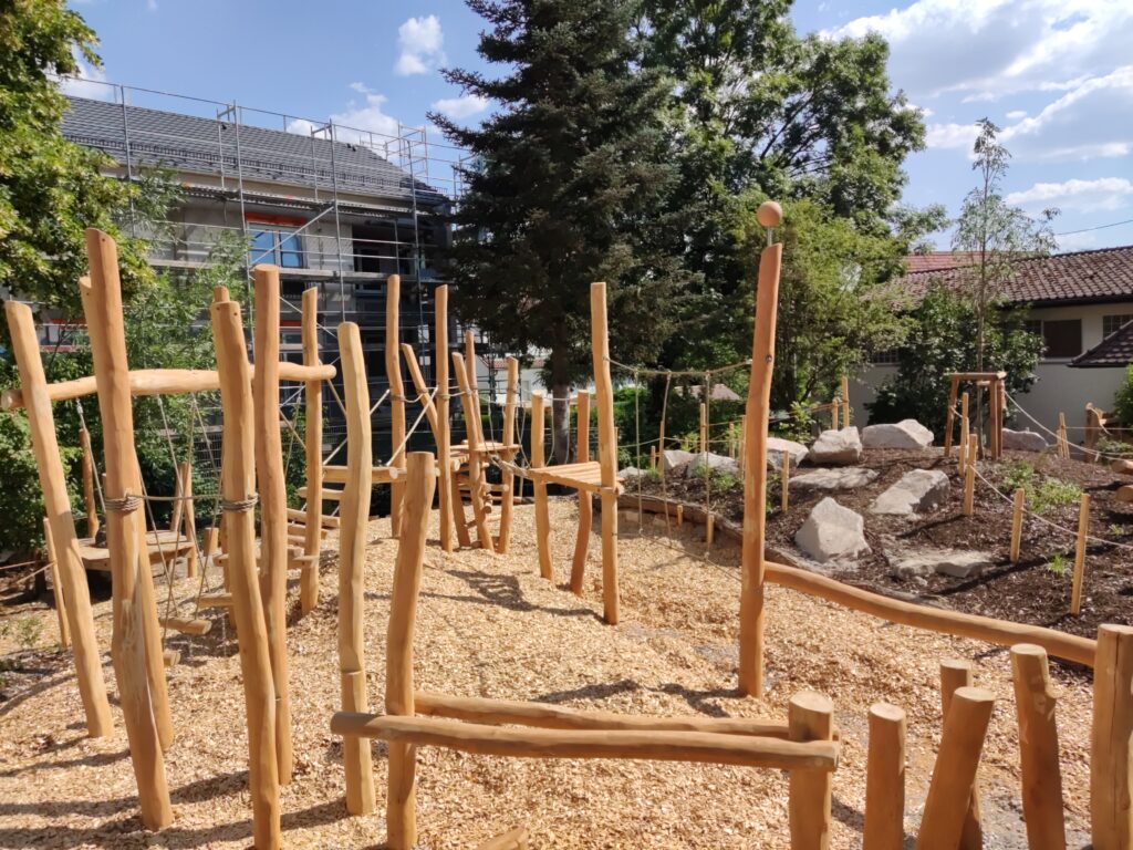 Holzkletteranlage und bepflanzter Schulhof im Hintergrund