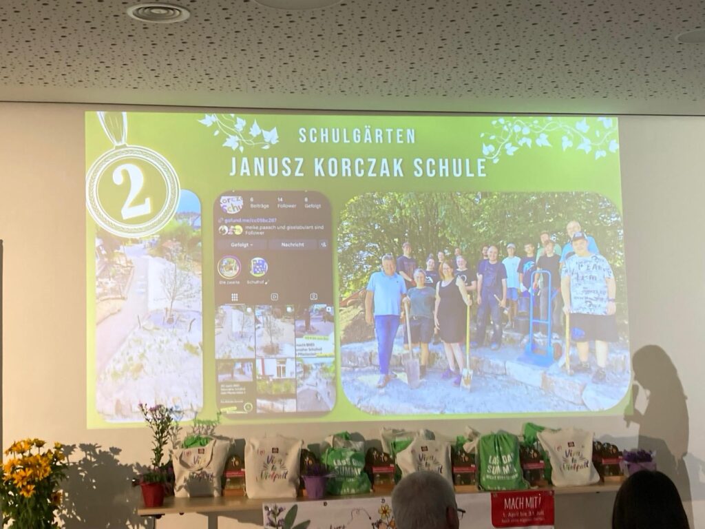 Präsentation mit der Überschrift "Schulgärten. Janus Korczak Schule" und Bilder vom Team der Mitmachaustelle, dem Instagramprofil des Schulprojekts sowie einem Teil des umgestalteten Schulhof.